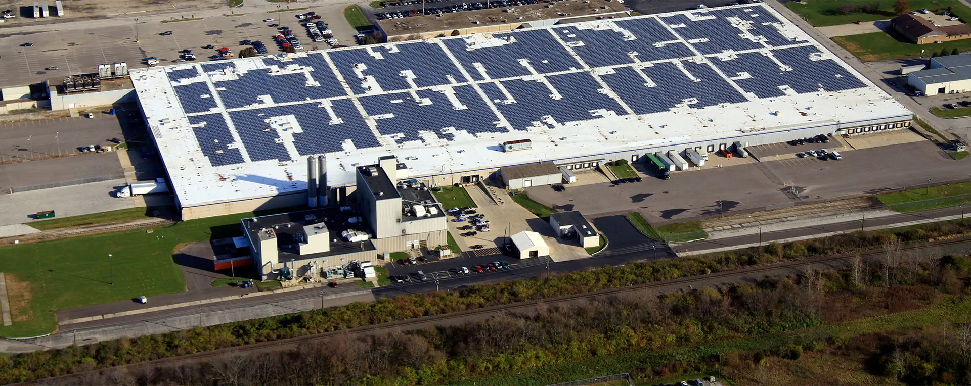 A large warehouse with many solar panels on the roof.